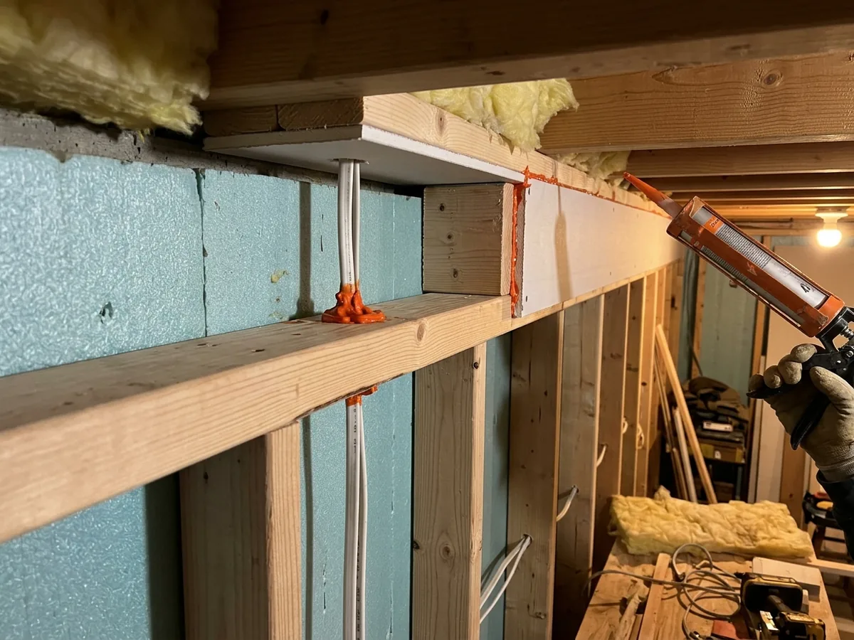 Fireblocking lumber installed at the top of a basement stud wall where it meets the floor joists